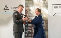 Vīrietis saņem balvu no sievietes  “Ilgtspējas līderis 2018”